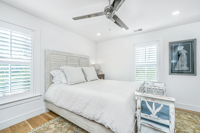 bedroom with multiple windows, ceiling fan, and wood-type flooring