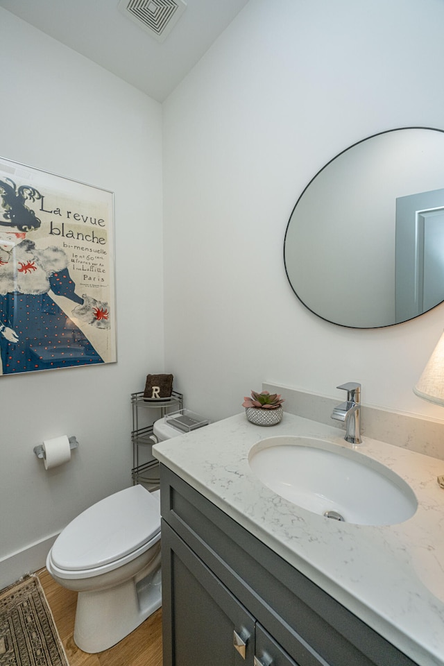 bathroom with hardwood / wood-style flooring, vanity, and toilet