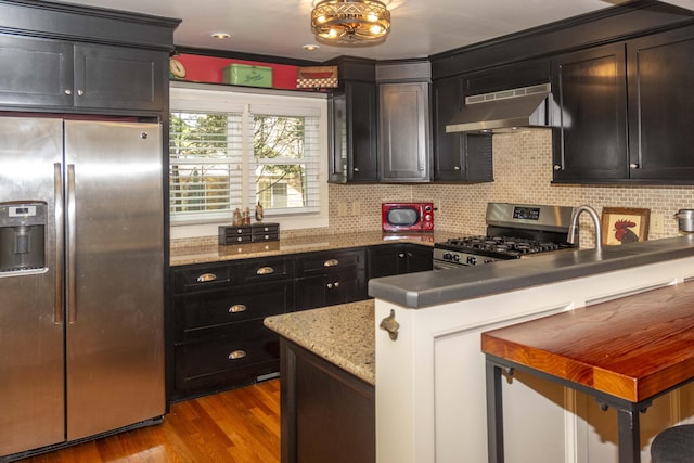 152 Mansfield Blvd, Charleston, SC 29418 - kitchen with appliances with stainless steel finishes, extractor fan, a peninsula, wood finished floors, and tasteful backsplash