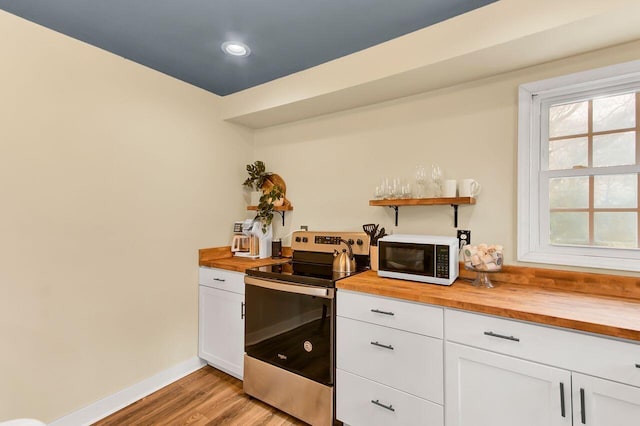 kitchen featuring butcher block counters, white cabinetry, light wood-type flooring, and stainless steel range with electric stovetop