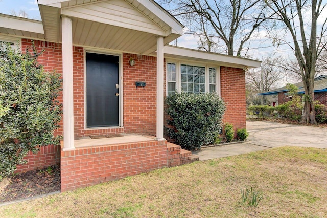 property entrance featuring brick siding and a yard