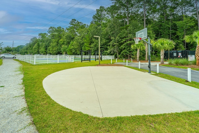 view of basketball court featuring community basketball court, a lawn, and fence