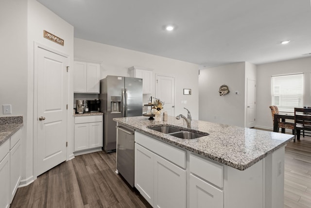 kitchen with sink, white cabinets, light stone counters, a center island with sink, and appliances with stainless steel finishes