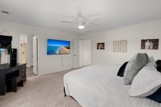 bedroom featuring ceiling fan, light colored carpet, and connected bathroom