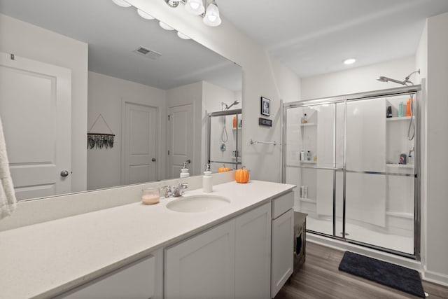 bathroom with walk in shower, vanity, and wood-type flooring