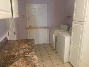 laundry room featuring washer and dryer, cabinets, and light tile floors