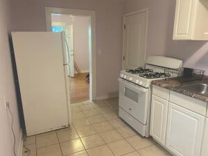 kitchen featuring white cabinets, white appliances, and light tile floors