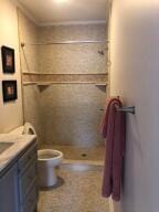 bathroom with tiled shower, vanity, and toilet