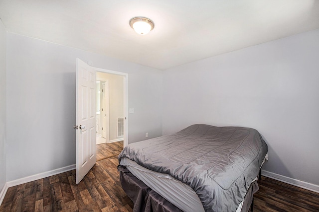 bedroom with baseboards, wood finished floors, and visible vents