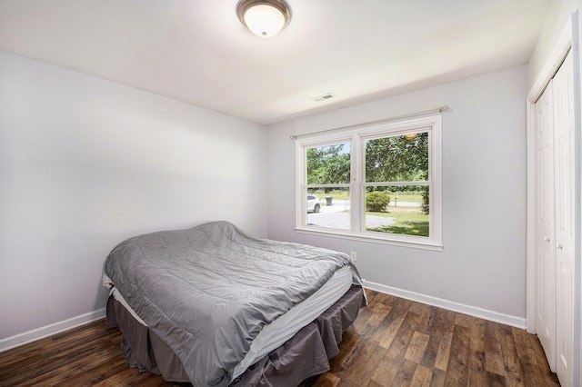 bedroom featuring visible vents, baseboards, wood finished floors, and a closet
