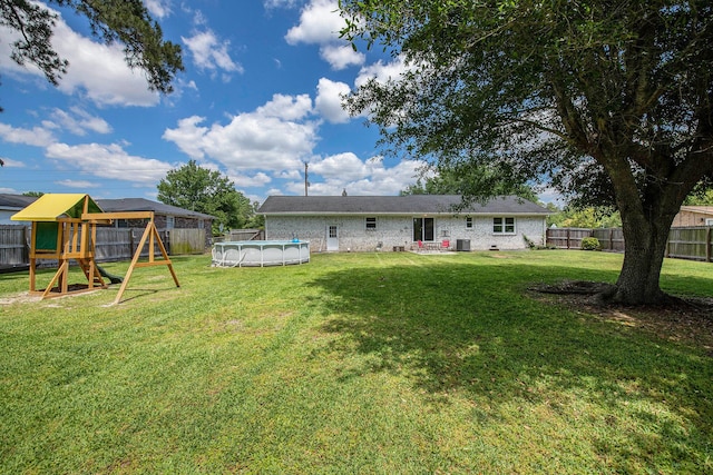 rear view of house featuring a fenced backyard, a playground, a yard, and a covered pool