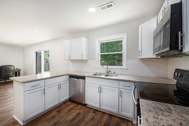 kitchen featuring visible vents, black electric range oven, dishwasher, a sink, and a peninsula