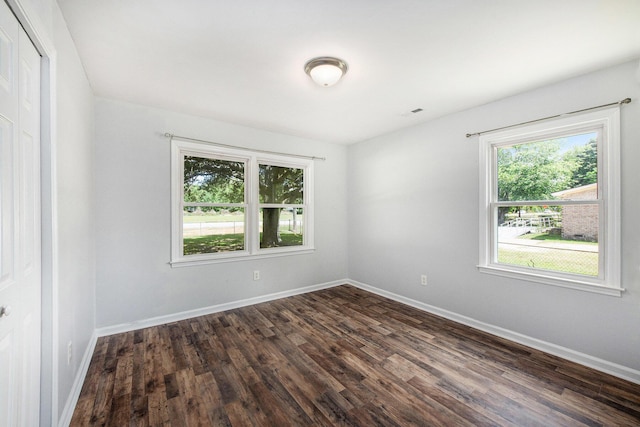unfurnished room featuring baseboards, dark wood-style flooring, and a healthy amount of sunlight