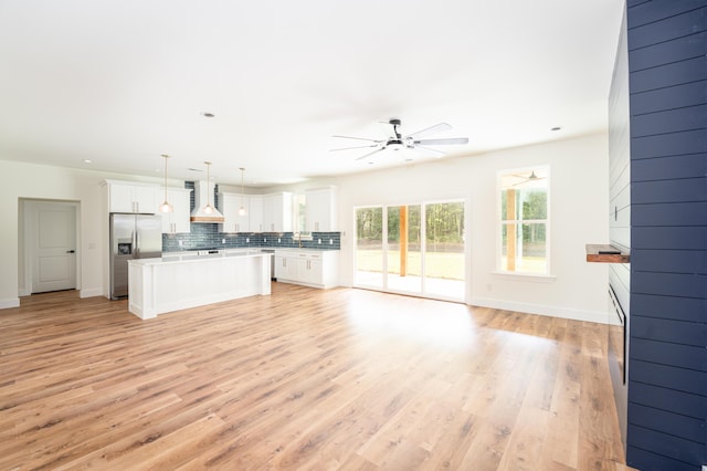 kitchen with a kitchen island, a ceiling fan, open floor plan, stainless steel fridge, and custom range hood
