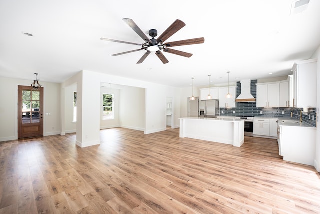 kitchen with a kitchen island, custom range hood, a sink, open floor plan, and stainless steel appliances