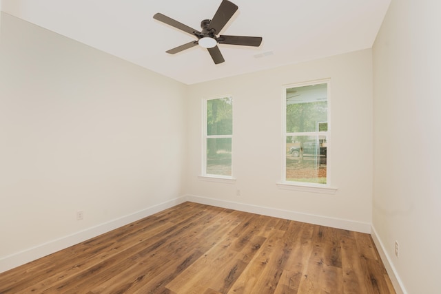 empty room featuring baseboards, ceiling fan, wood finished floors, and visible vents