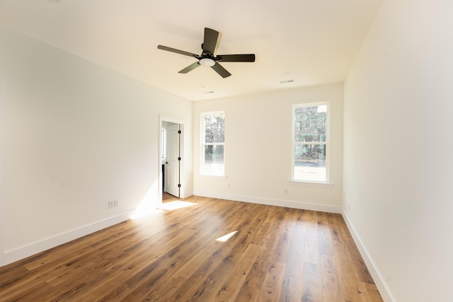 empty room with baseboards, ceiling fan, visible vents, and hardwood / wood-style floors