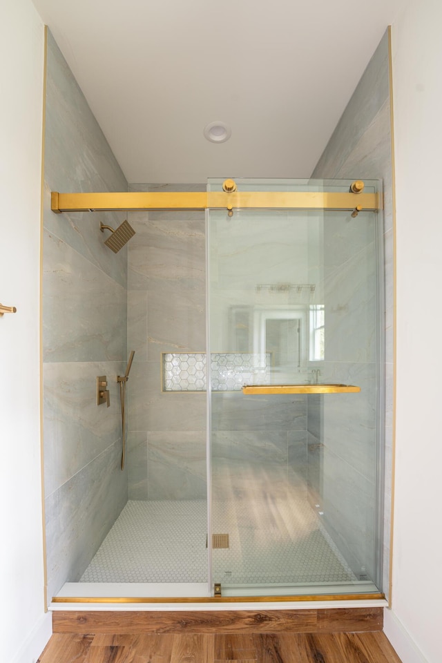 full bath with baseboards, wood finished floors, and a shower stall