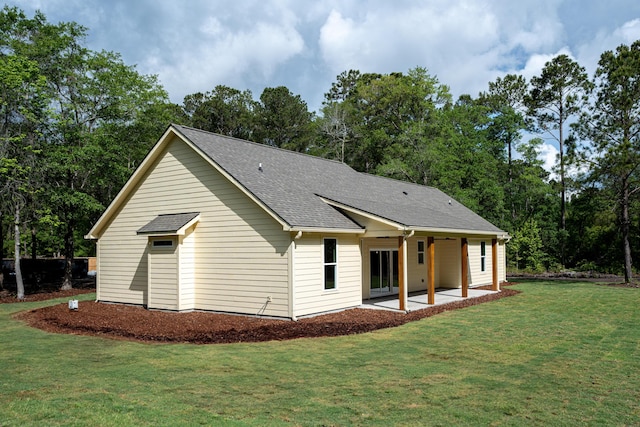 rear view of house with a lawn, roof with shingles, and a patio area