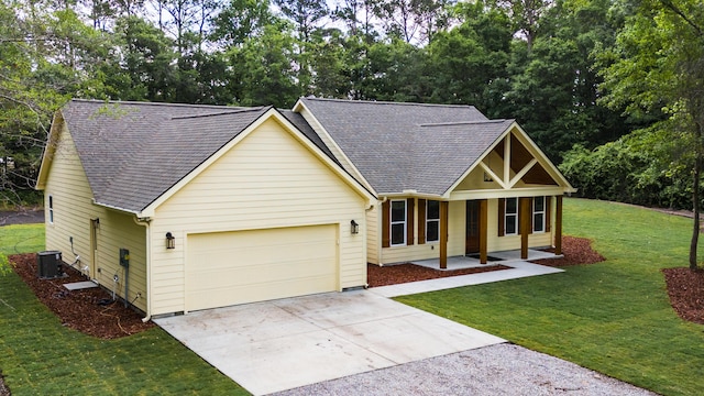 view of front of house with a shingled roof, an attached garage, a front yard, concrete driveway, and covered porch