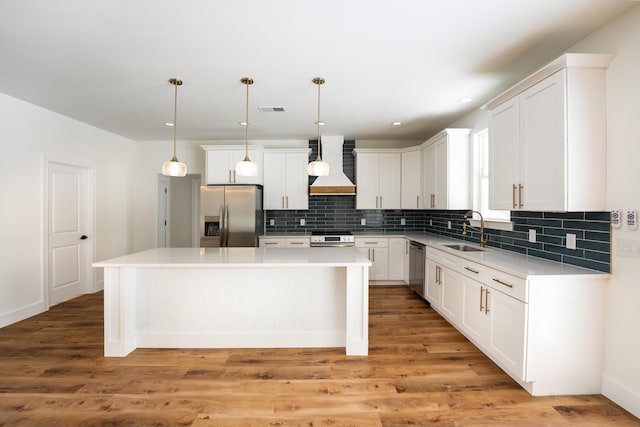 kitchen with a sink, stainless steel appliances, a kitchen island, visible vents, and custom exhaust hood