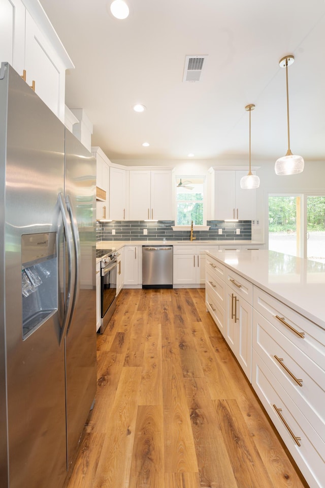 kitchen featuring light countertops, tasteful backsplash, stainless steel appliances, and visible vents