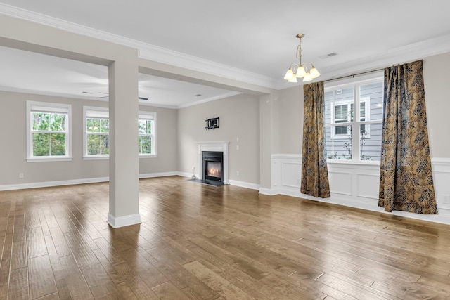 unfurnished living room with wood-type flooring, a chandelier, and crown molding