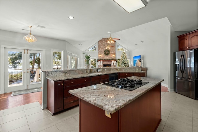 kitchen featuring black appliances, a spacious island, vaulted ceiling, ceiling fan, and decorative light fixtures