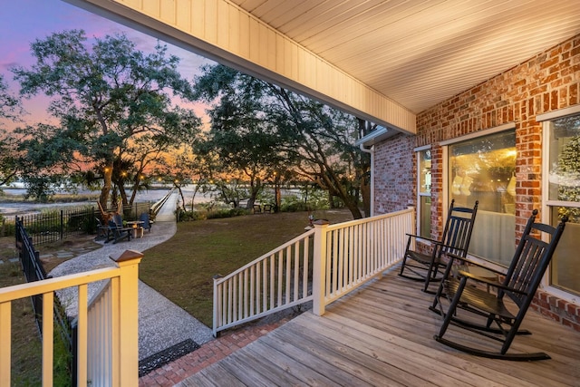 deck at dusk featuring a lawn