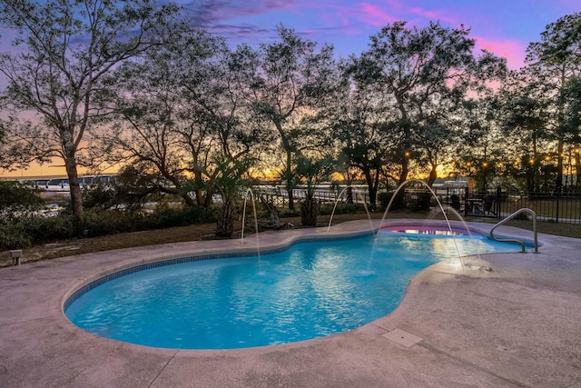 pool at dusk featuring a patio area and pool water feature