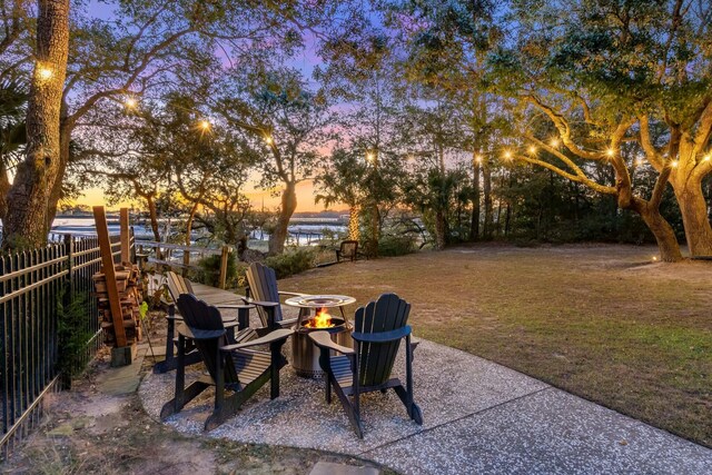 yard at dusk featuring a water view and a fire pit