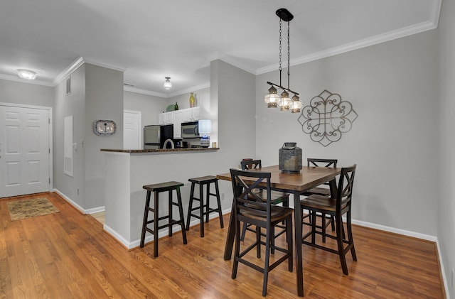 dining room featuring visible vents, crown molding, baseboards, and wood finished floors