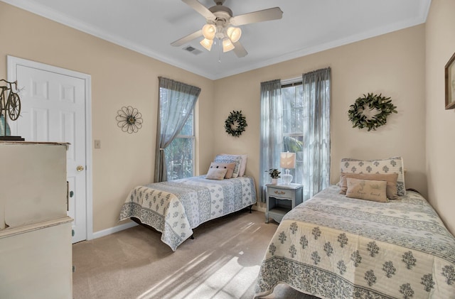 carpeted bedroom featuring ornamental molding, a ceiling fan, visible vents, and baseboards