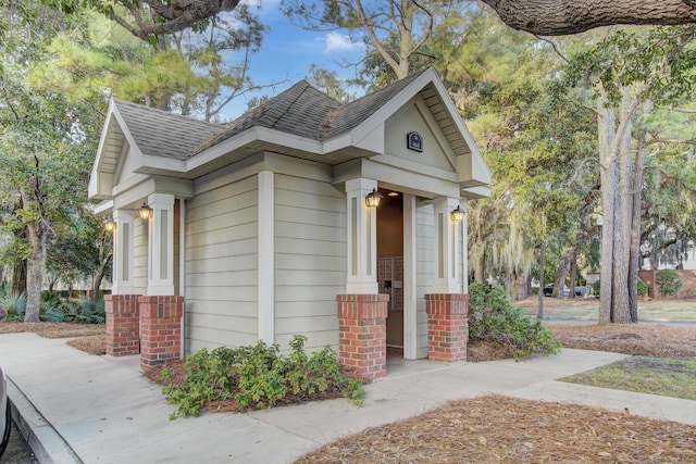 exterior space with a shingled roof and brick siding