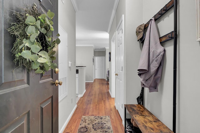 interior space featuring ornamental molding, light wood-style flooring, and baseboards