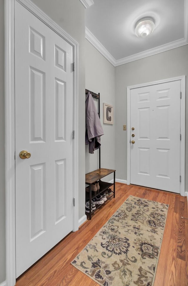 foyer entrance with baseboards, crown molding, and light wood finished floors