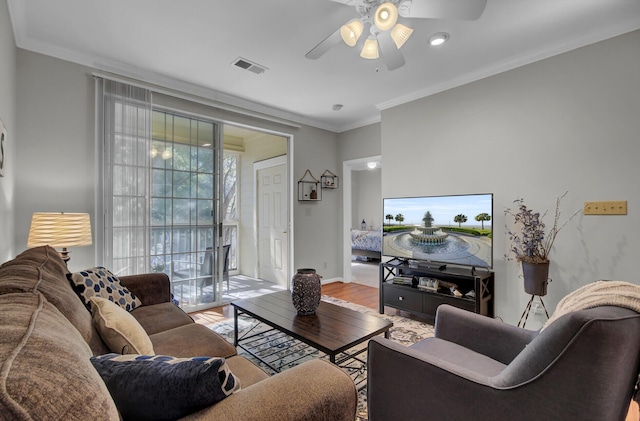 living area featuring crown molding, visible vents, ceiling fan, wood finished floors, and baseboards