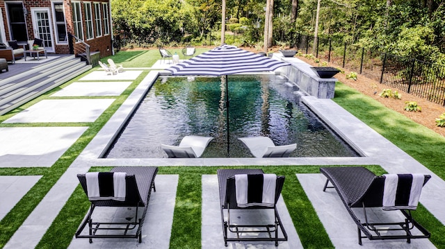 view of swimming pool featuring a deck, a fenced backyard, a fenced in pool, and a lawn