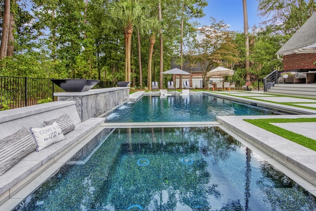 view of pool with a patio, fence, and a pool with connected hot tub