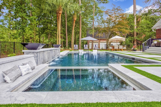 view of swimming pool featuring a patio area, fence, and a pool with connected hot tub