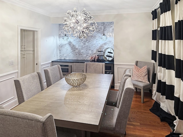 dining area with a wainscoted wall, dark wood finished floors, ornamental molding, a decorative wall, and a chandelier