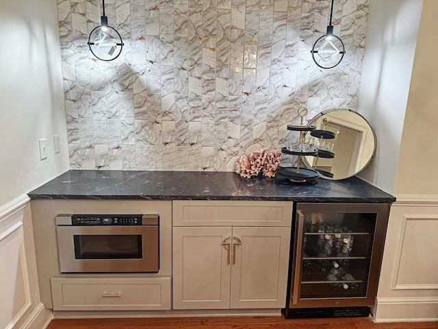 bar with beverage cooler, hanging light fixtures, a dry bar, and oven