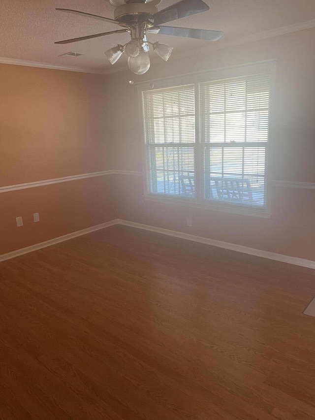 unfurnished room featuring baseboards, crown molding, wood finished floors, and a healthy amount of sunlight