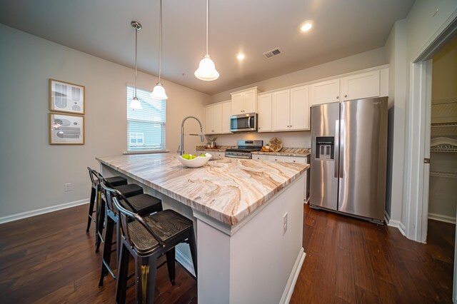 kitchen featuring white cabinetry, hanging light fixtures, light stone countertops, dark hardwood / wood-style floors, and appliances with stainless steel finishes