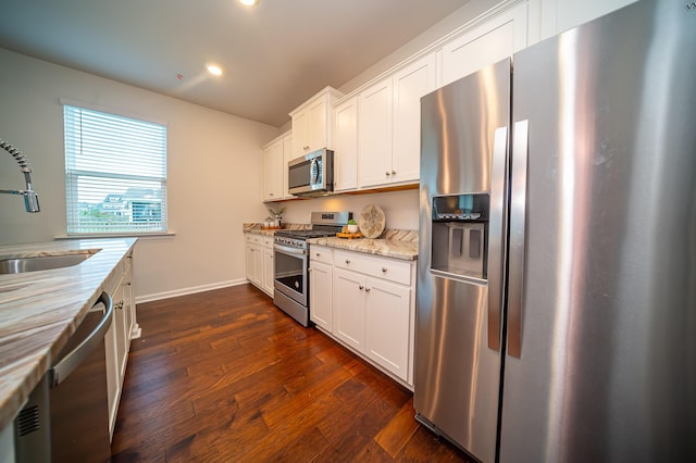 kitchen featuring white cabinets, dark hardwood / wood-style floors, light stone countertops, appliances with stainless steel finishes, and sink