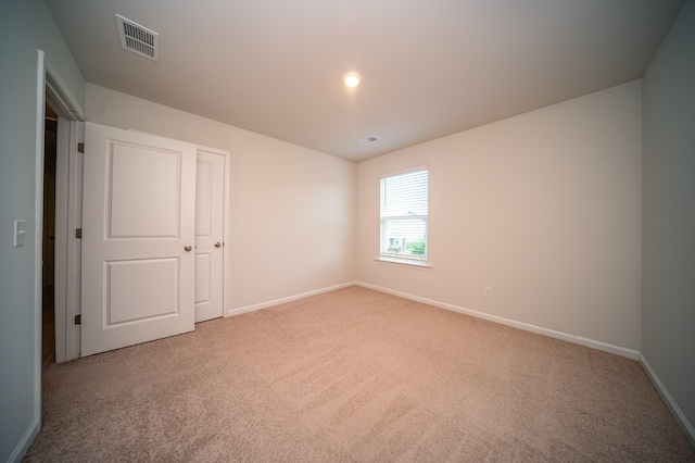 unfurnished bedroom featuring light carpet and a closet