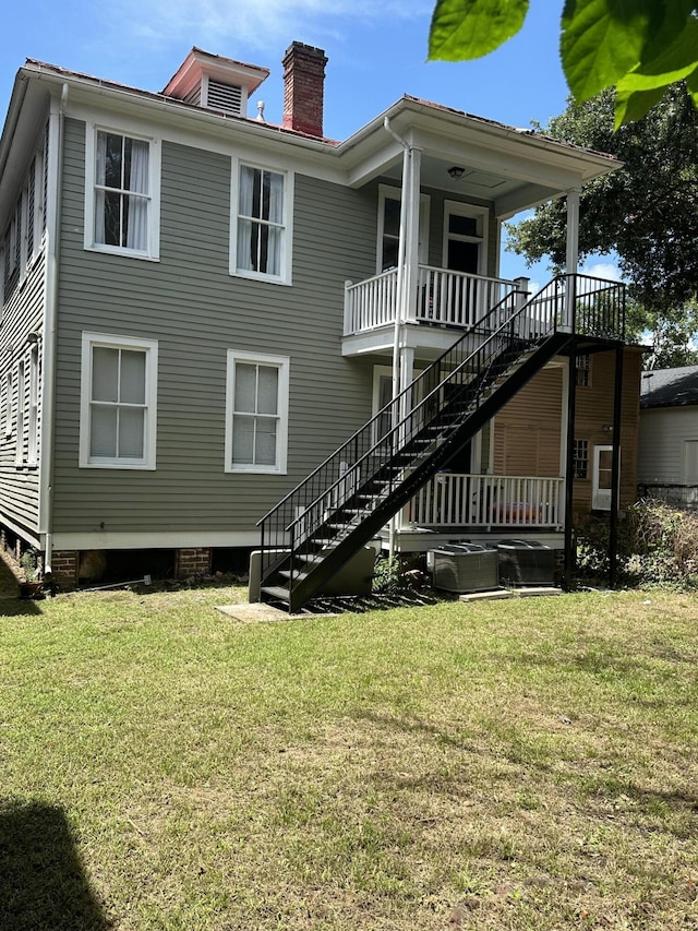 back of property with central AC and a lawn