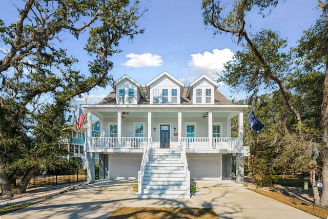 coastal home with a porch, concrete driveway, ceiling fan, and stairs