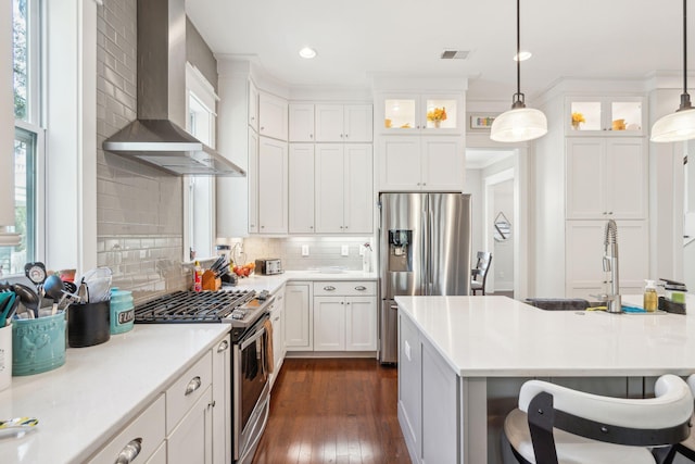 kitchen with visible vents, decorative backsplash, glass insert cabinets, stainless steel appliances, and wall chimney range hood