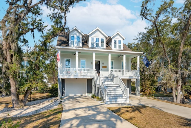 beach home featuring a porch, fence, a ceiling fan, driveway, and stairway